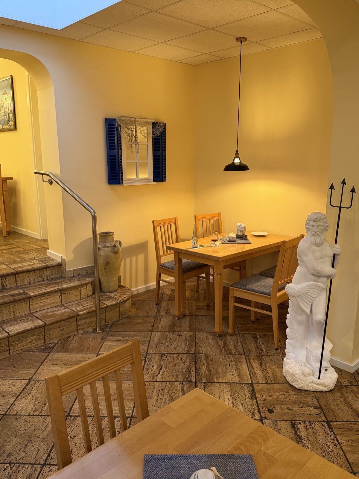 Gastraum der Taverne Artemis mit Poseidon-Figur und blauen Fensterläden